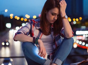 Unhappy woman sitting thoughtfully at the bridge